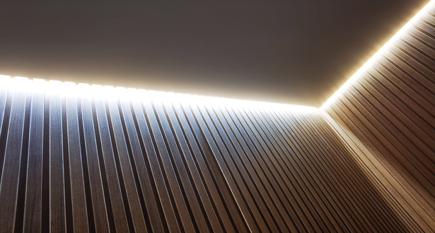 Lumină LED continuă între tavanul extensibil și riflaje decorative din lemn, cu efect cald difuz