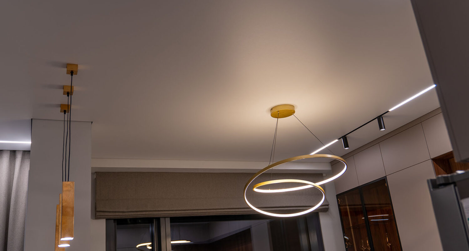 Bucătărie cu tavan extensibil, șină magnetică cu spoturi și linie LED, lustră aurie cu cercuri și pendule din lemn